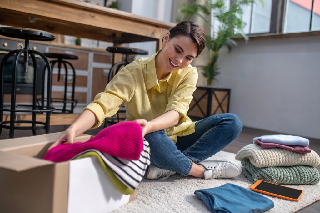 Woman packing sweaters and other clothes into a box