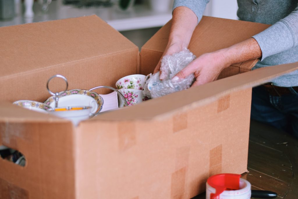 Woman packing fine china dishes into a cardboard box