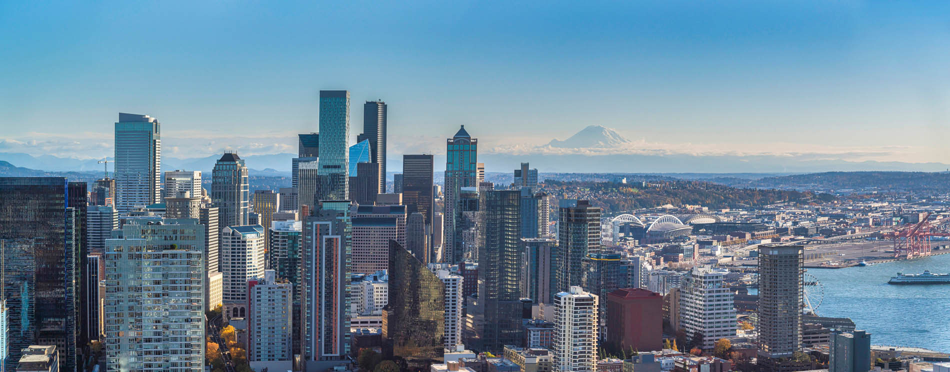 Cityscape view from the Space Needle at Tacoma, Washington, United States. Skyscrapers near the bay with ships and a view of a mountain and sky at the background.